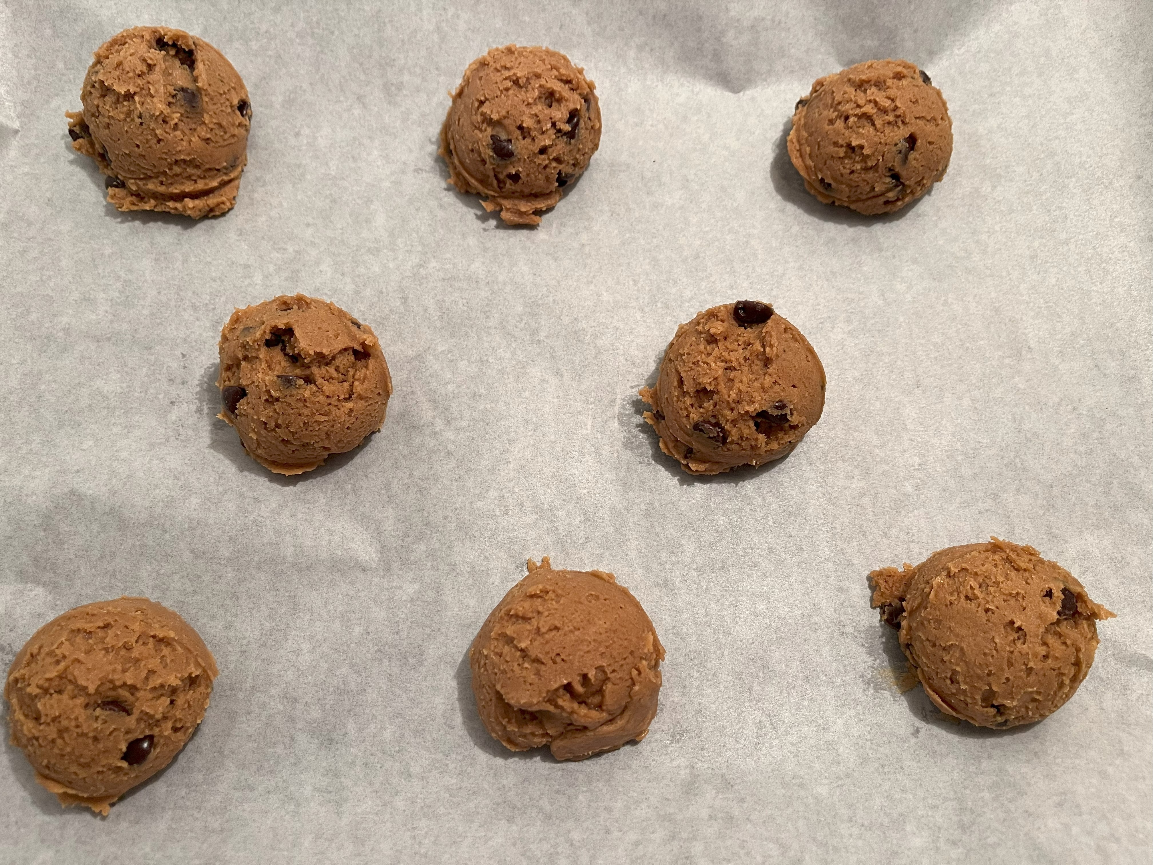 Cookie dough balls on a prepared baking sheet.