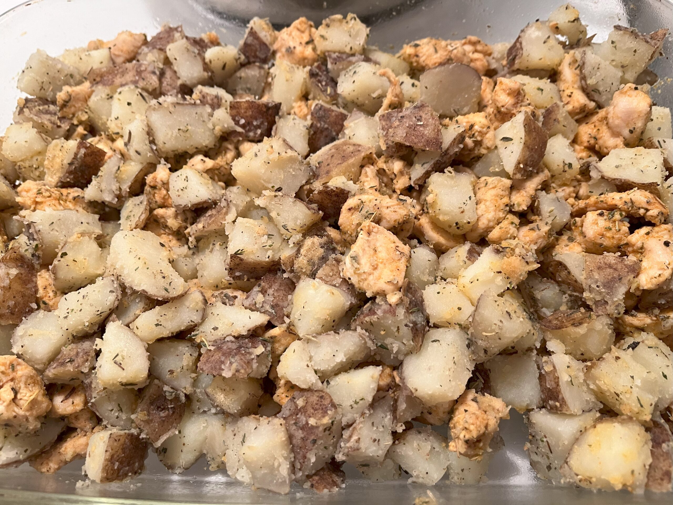 Assembling the casserole — the chicken and potatoes are layered together in a glass dish.
