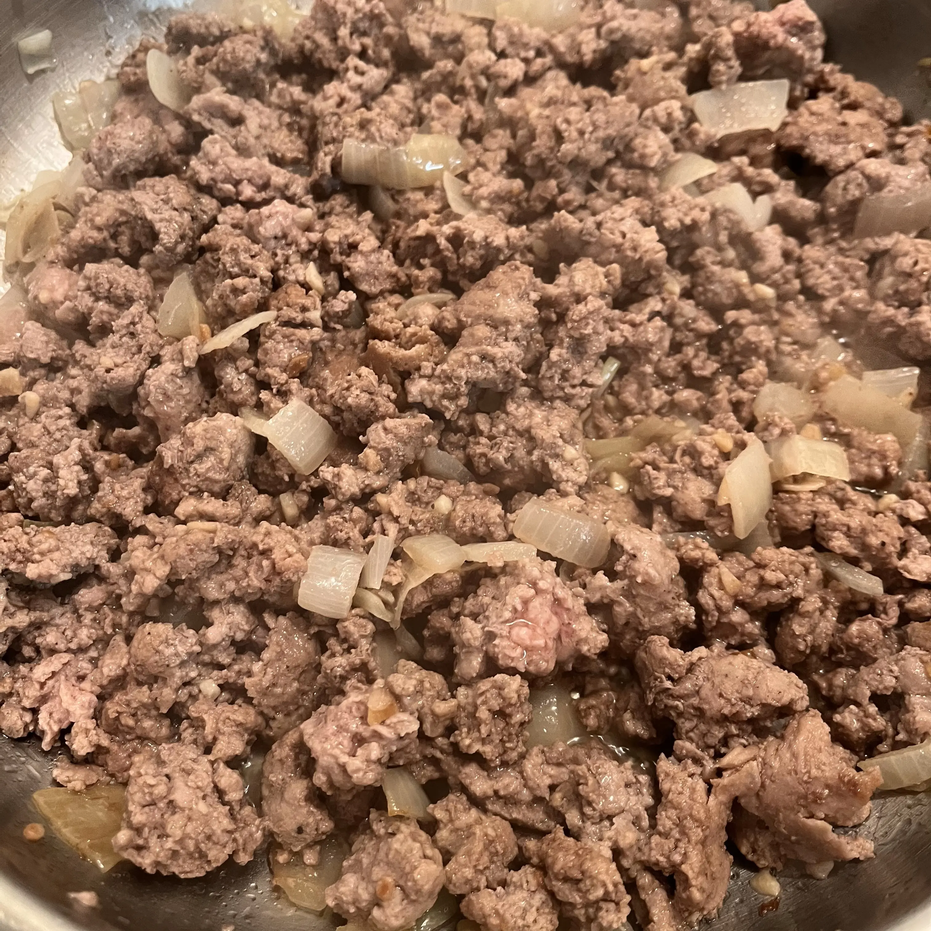 Ground beef, onions, and garlic cooking in a pan.