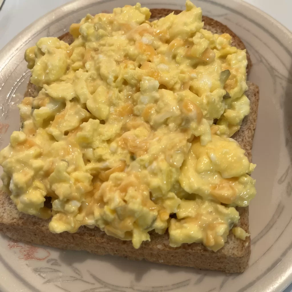 Egg salad on a piece of whole wheat bread.