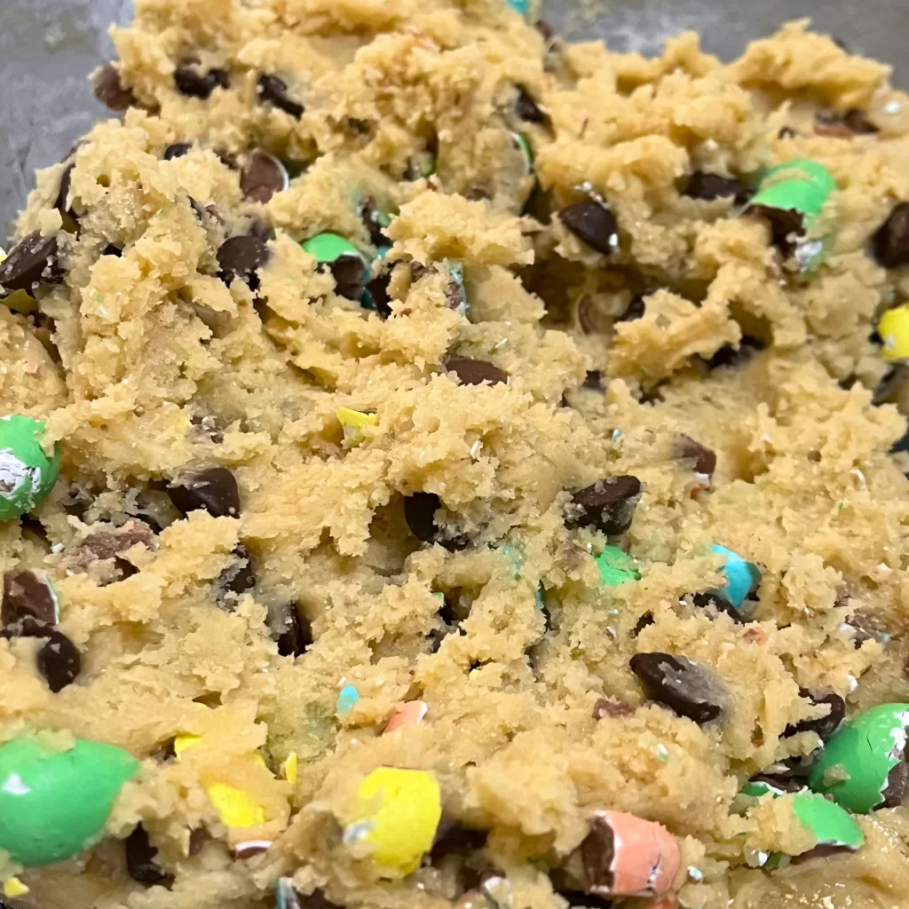 Cookie dough with chocolate chips and Mini Eggs pieces, in a metal bowl.