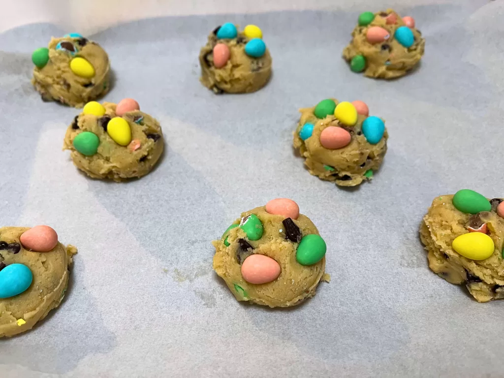 Mini Egg cookie dough balls on a parchment paper-lined baking sheet.