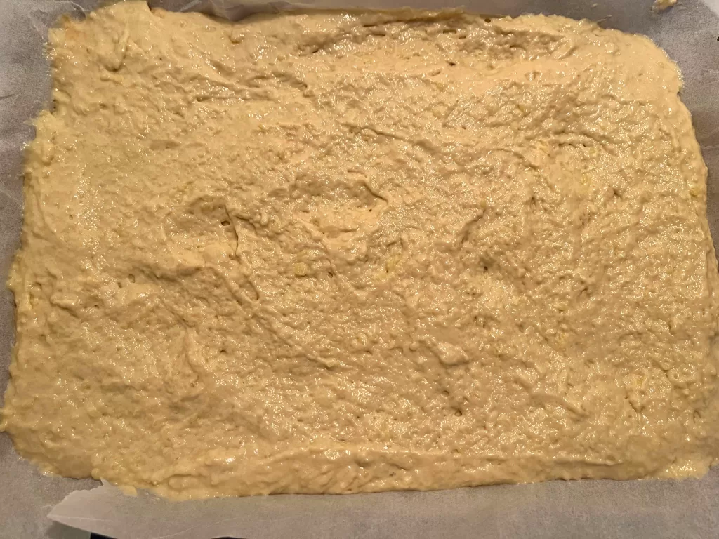 Pancake batter spread out on a parchment paper-lined baking sheet.