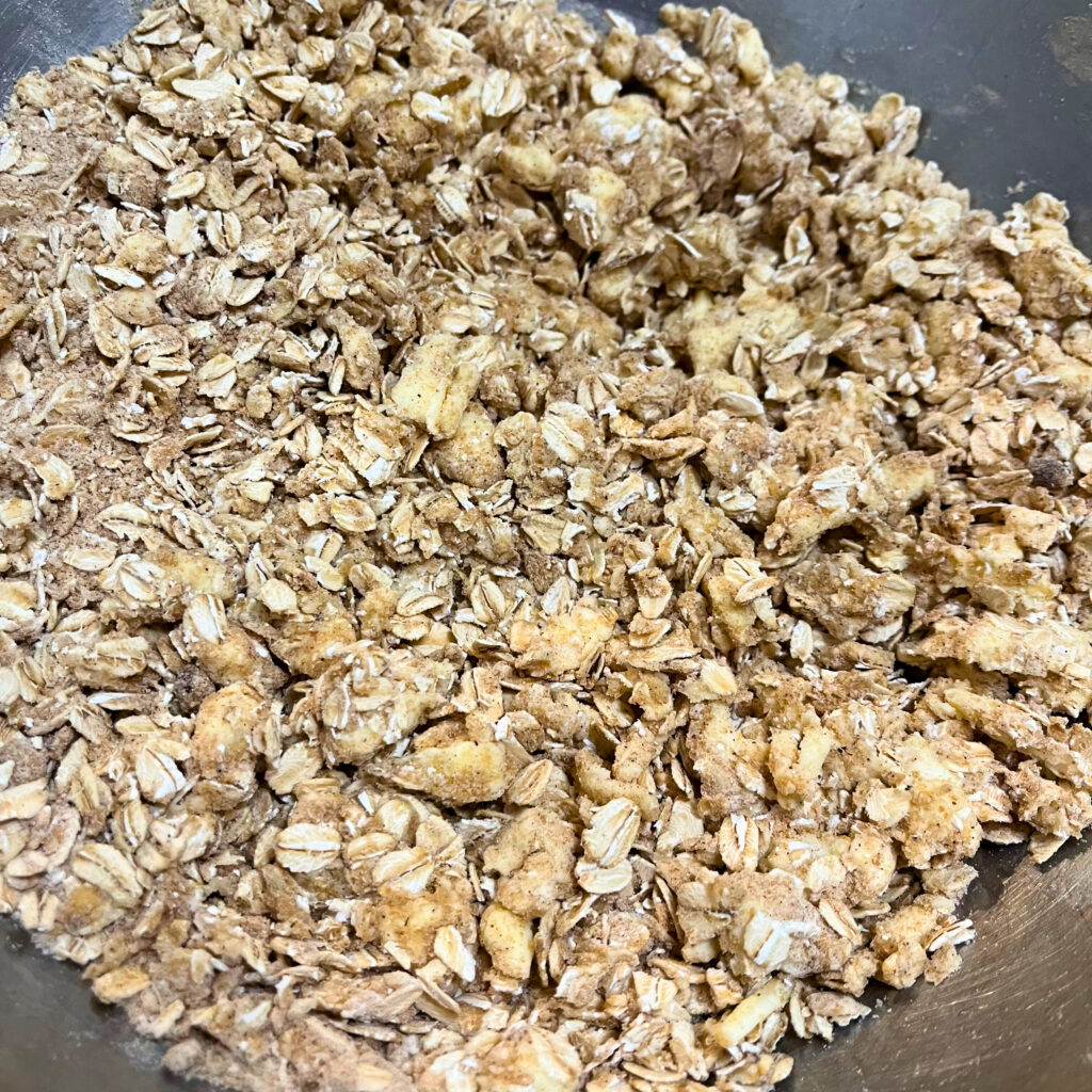 Crisp topping made from butter, oats, flour, brown sugar, salt, cinnamon, nutmeg, and ginger in a metal mixing bowl.